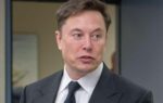 Elon Musk in business suit holding phone during 2019 visit to military aerospace command headquarters in Colorado Springs
