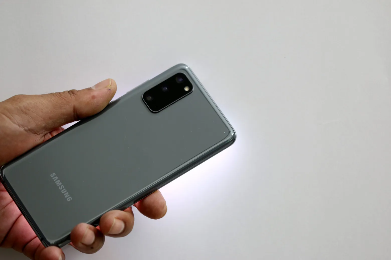 Person holding Samsung Galaxy S20 smartphone showing back panel with Samsung branding and camera module
