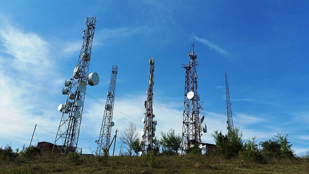Telecommunications towers with lattice steel construction standing against blue sky in Senaki, Georgia.