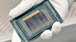 A gloved technician holds a chip module inside Intel’s Fab 52 cleanroom.