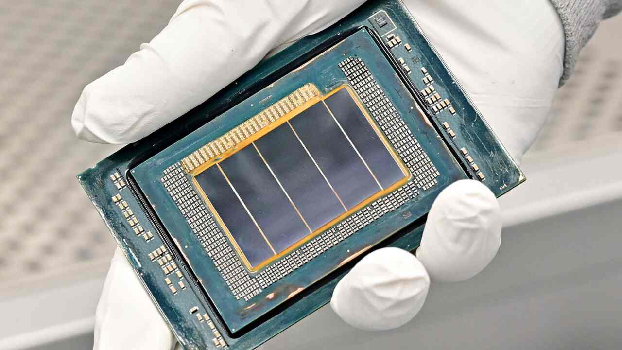 A gloved technician holds a chip module inside Intel’s Fab 52 cleanroom.