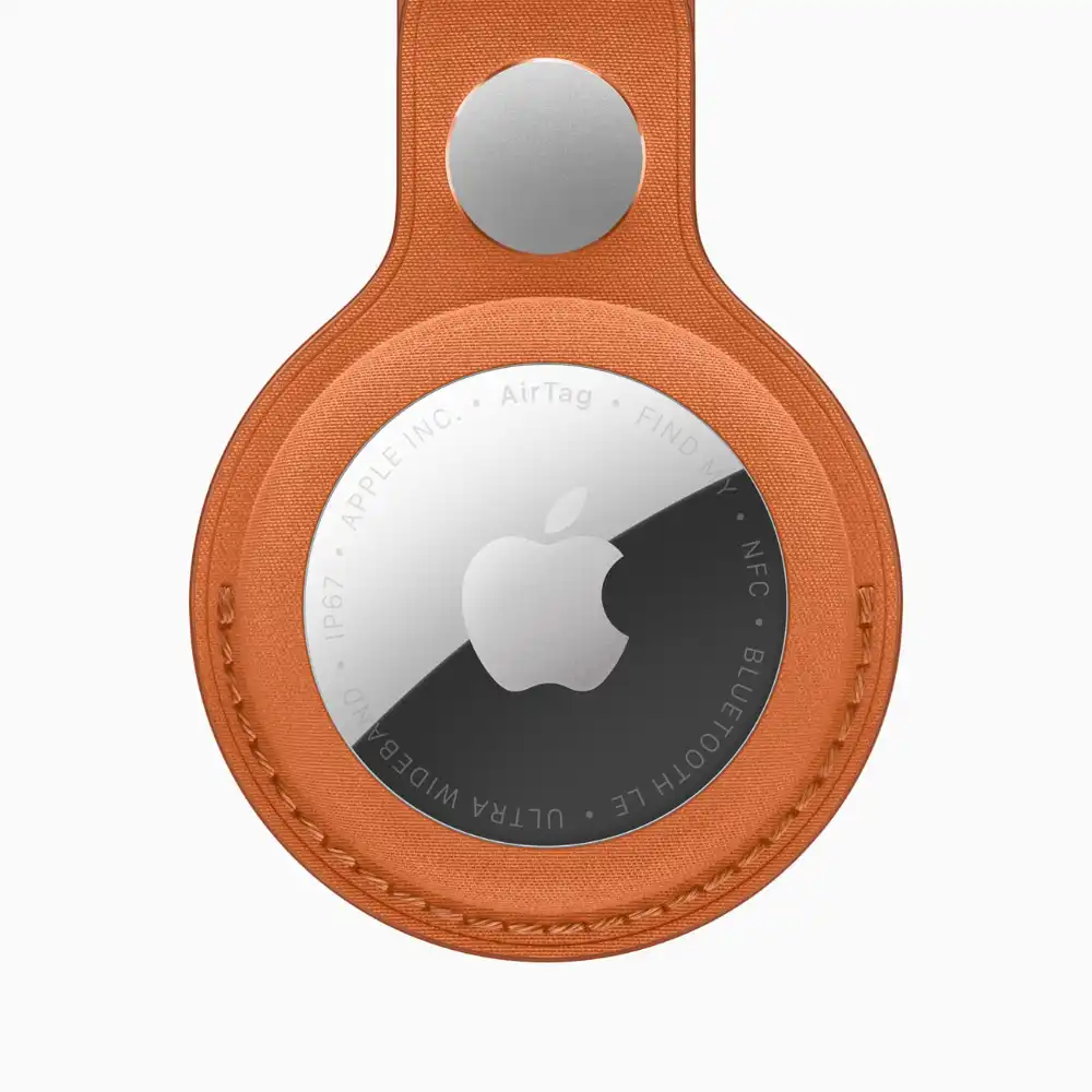 Apple AirTag attached to FineWoven Key Ring in multiple color options including fox orange, midnight purple, navy, moss, and black against white background