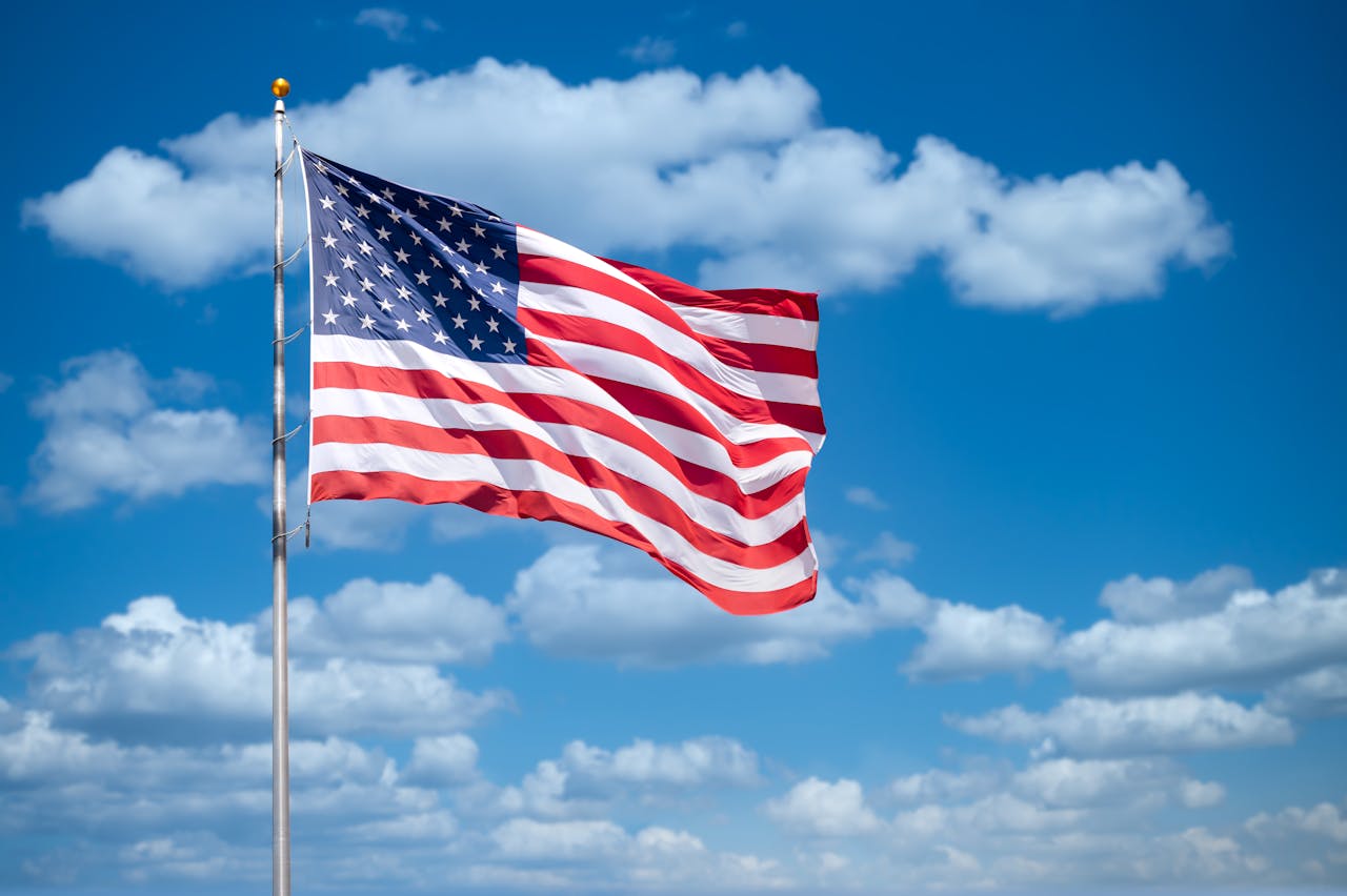 American flag waving against clear blue sky symbolizing national security concerns over massive government contractor data breach affecting millions of US citizens