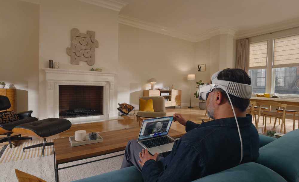 Apple Vision Pro headset user viewing multiple floating application windows in spatial computing environment showing productivity workspace with infinite digital canvas