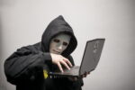 A shadowed hand with digital code overlay representing a cybersecurity threat or hacker activity