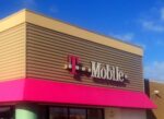 T-Mobile store exterior with illuminated magenta signage displaying company logo and branding on commercial building facade
