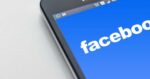Facebook logo displayed on a smartphone screen against a dark background