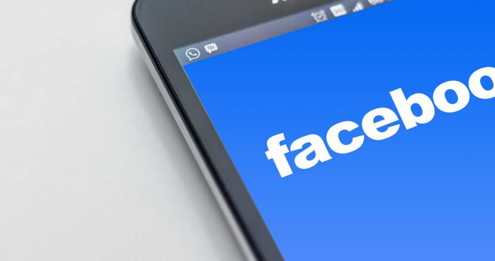 Facebook logo displayed on a smartphone screen against a dark background