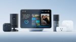 Amazon Echo Show 8 smart display with a colorful smart home interface on screen, sitting on a wooden table in a modern living room setting
